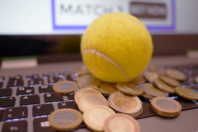 Auf der Tastatur eines Laptops liegen ein Tennisball sowie mehrere Euro-Münzen im Wert von ein und zwei Euro.